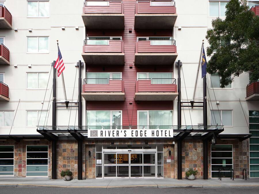 Ein mehrstöckiges Hotel mit einem zentralen Eingang, Balkonen und einer US-amerikanischen Flagge.