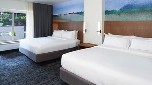 Habitació d'hotel amb dos llits, una finestra gran amb cortines i un quadre a la paret.