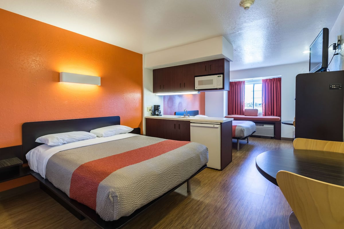 Una habitación de hotel con una cama, un escritorio, un microondas, un refrigerador y una televisión.