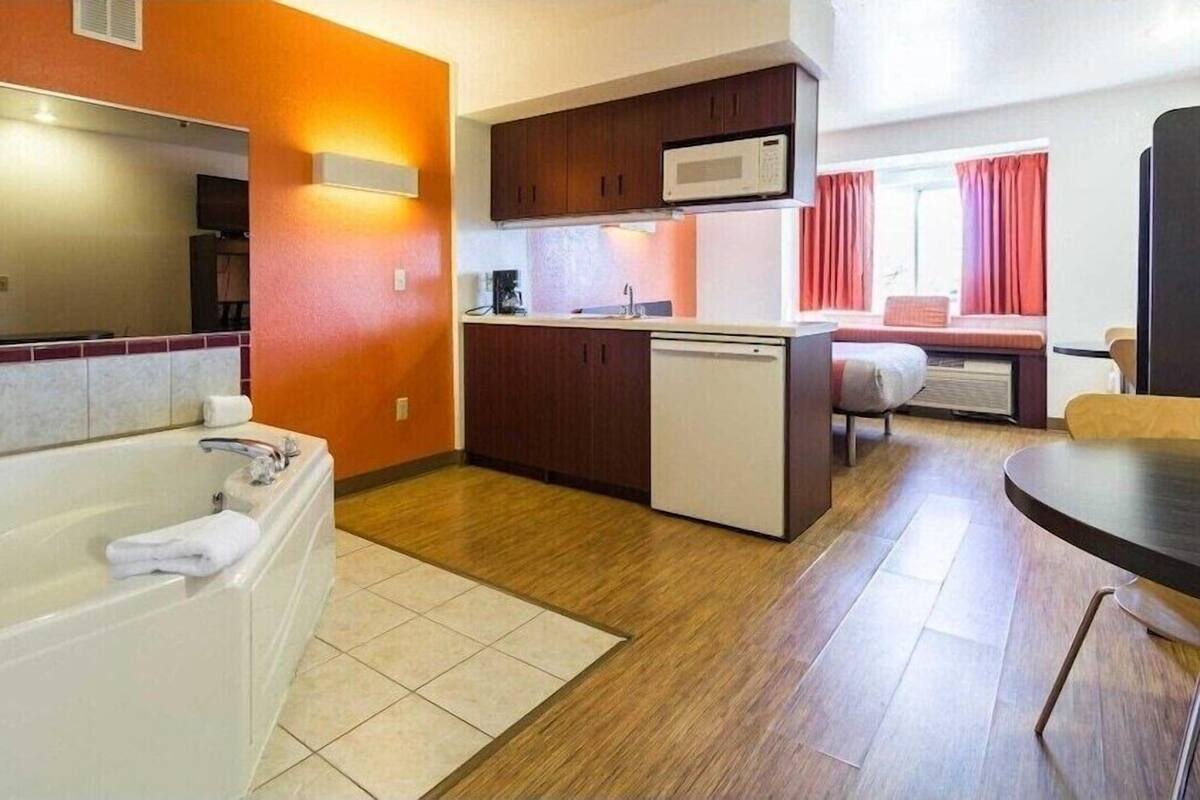 Habitación de hotel compacta con baño, kitchenette y un pequeño comedor.