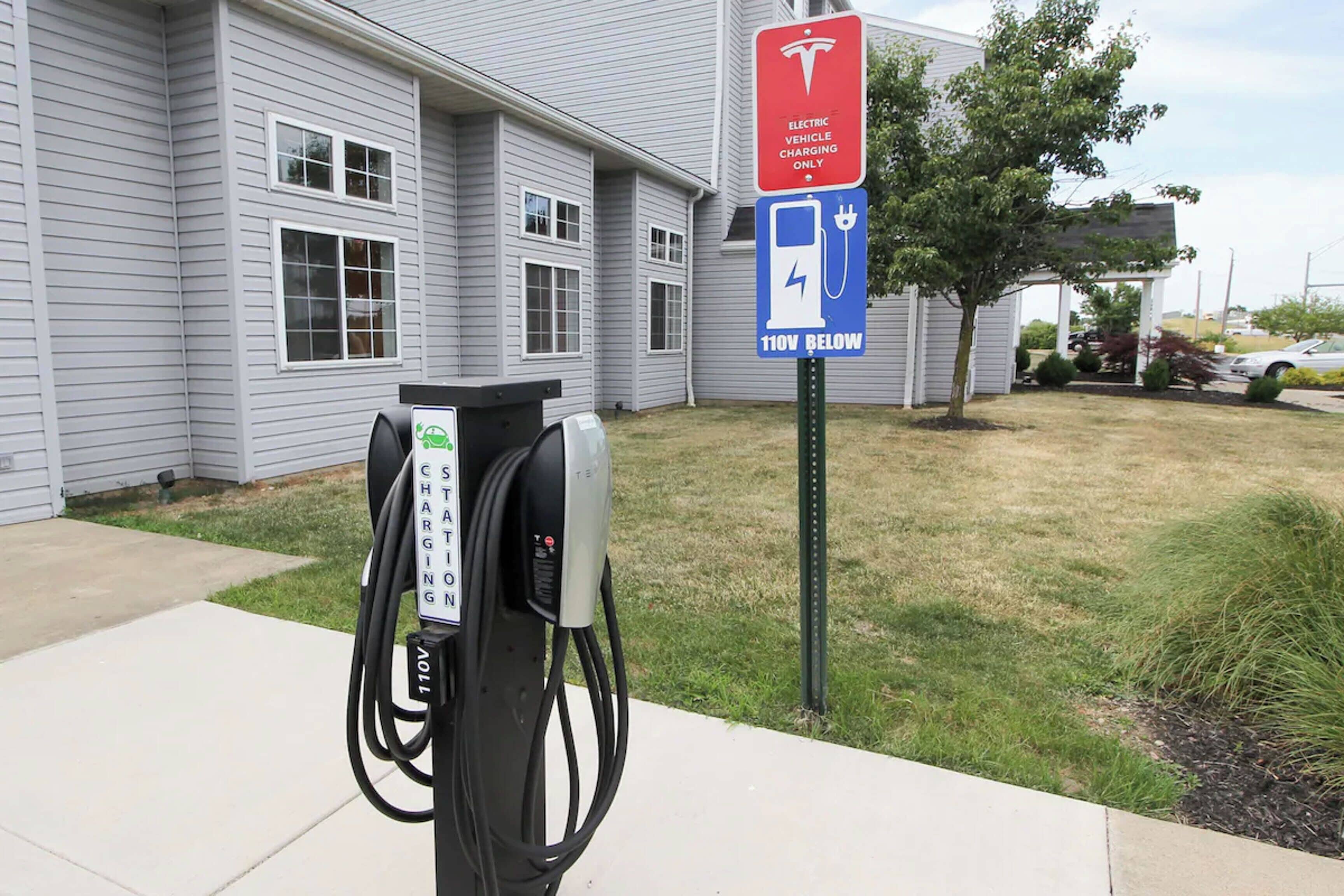 Une borne de recharge pour véhicules électriques, avec un panneau indiquant qu’elle est réservée aux véhicules nécessitant une tension de 110 V ou inférieure.