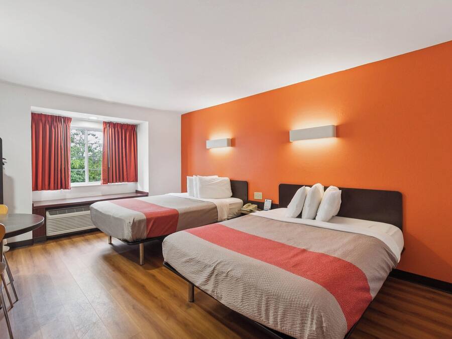 A hotel room with two beds, a desk, and a chair.