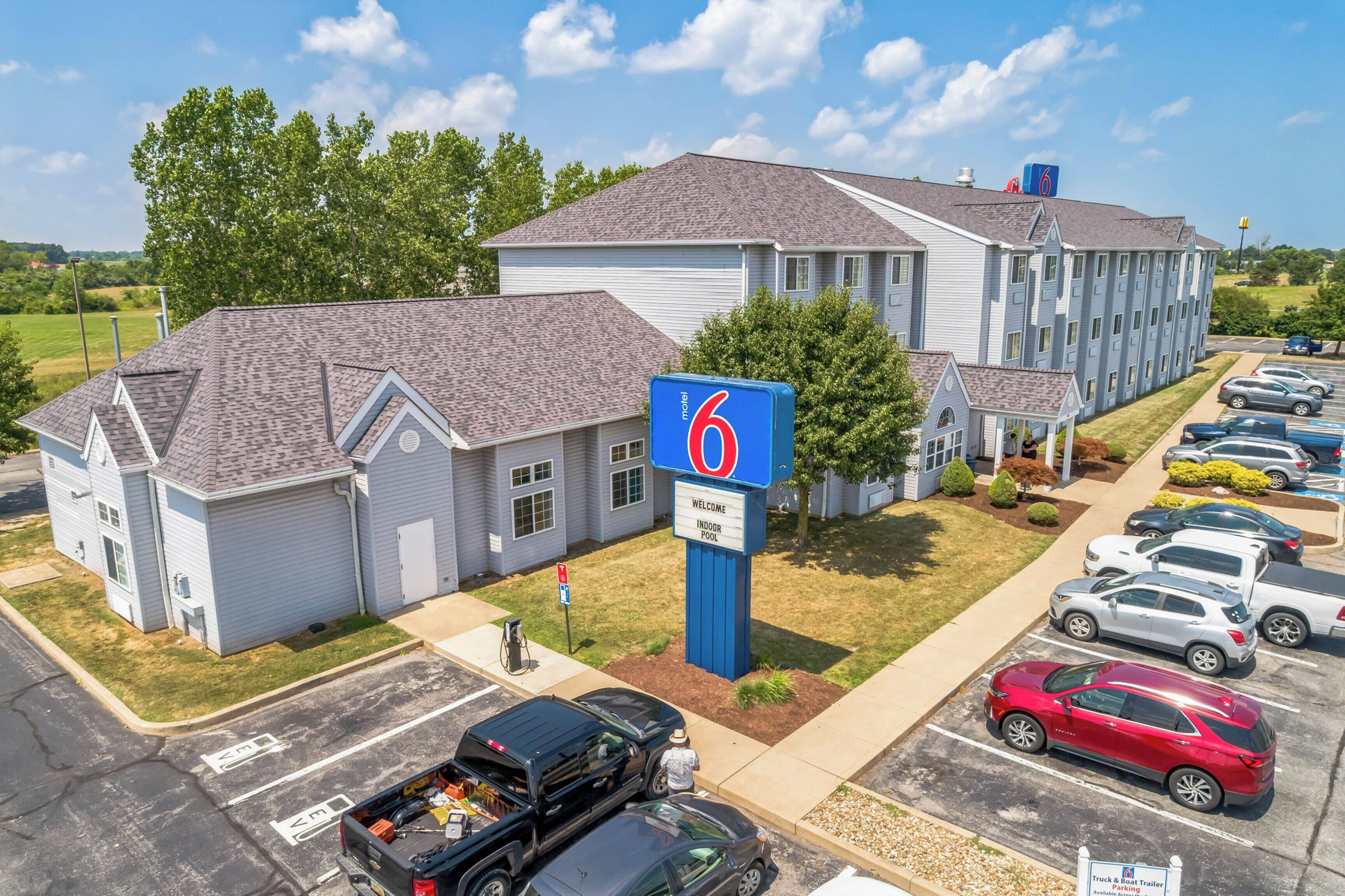 A motel with a large sign, a parking lot, and a building with multiple windows.