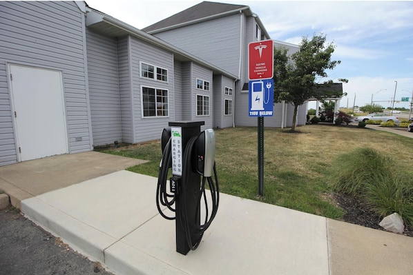 Eine Ladestation für Elektrofahrzeuge mit Schild, das anzeigt, dass sie nur für Elektrofahrzeuge zugänglich ist, und einer 110V-Steckdose.