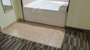 A bathroom with a bathtub, a mirror, and a striped carpet.