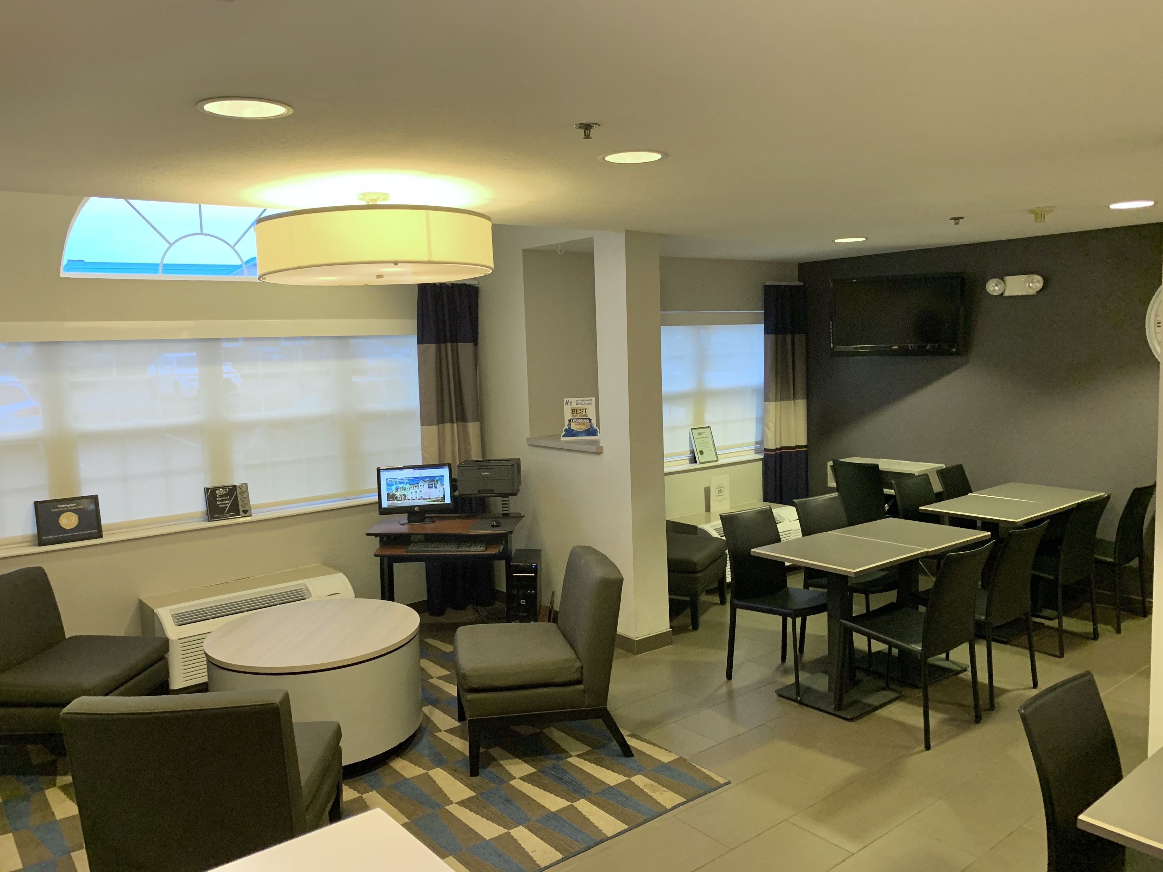 Une chambre d’hôtel comprenant un coin repas, un bureau avec un ordinateur et un téléviseur fixé au mur.