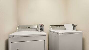 Two front-loading washing machines in a corner with a plain wall.