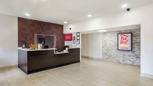 Zona de recepción de un hotel con diseño moderno, un mostrador de recepción y un cartel adosado que anuncia Red Roof Plus Suites.