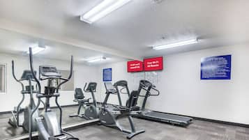 Sala de ginástica com diversos equipamentos de exercício, incluindo esteiras e elípticos.