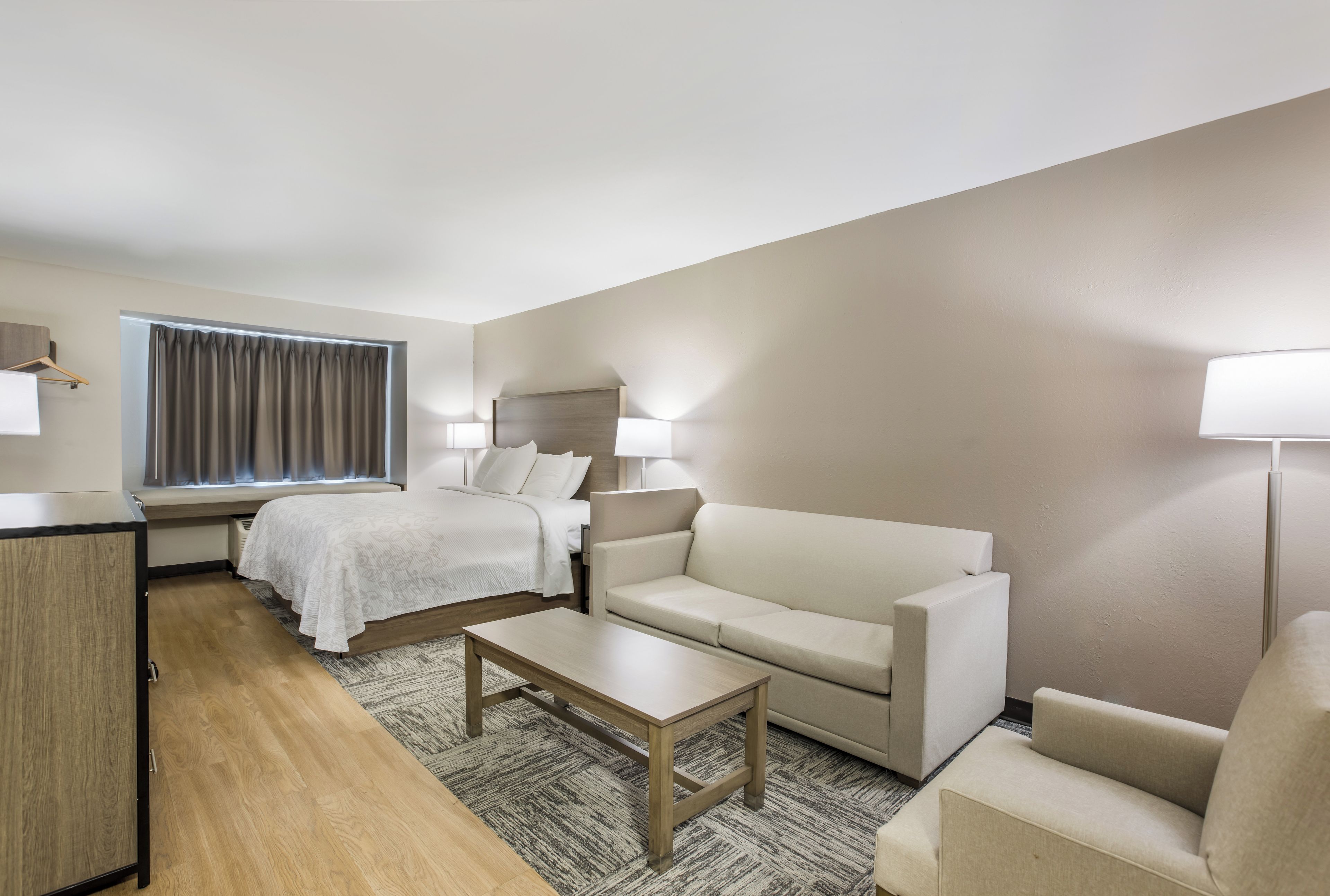 A hotel room with a bed, a sofa, a small table, and a desk.