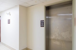 A hallway with an elevator and directional signs indicating amenities such as a pool, barber, and laundry services. - Red Roof Inn PLUS+ & Suites Savannah - I-95 (Savannah)