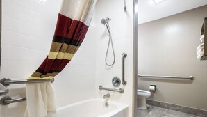 A bathroom with a bathtub, shower, toilet, and handrails. - Red Roof Inn PLUS+ & Suites Savannah - I-95 (Savannah)