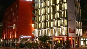 Un bâtiment CITYHOTEL à plusieurs étages, avec un bar bien visible et une enseigne pour le restaurant L'OSTERIA.