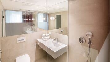 A modern bathroom with a glass-enclosed shower, a white sink, and a toilet.