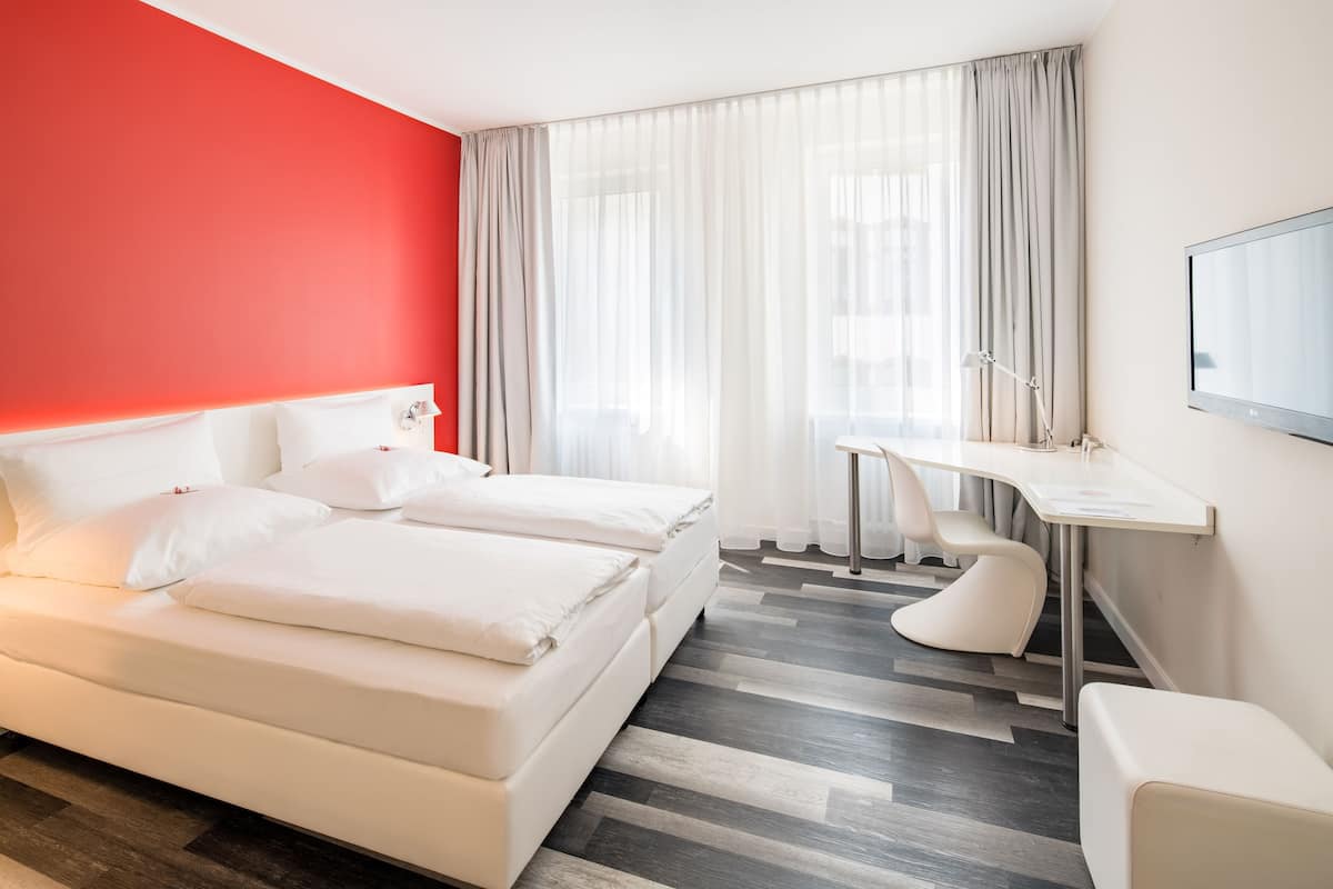 A hotel room with a bed, a desk, and a chair.