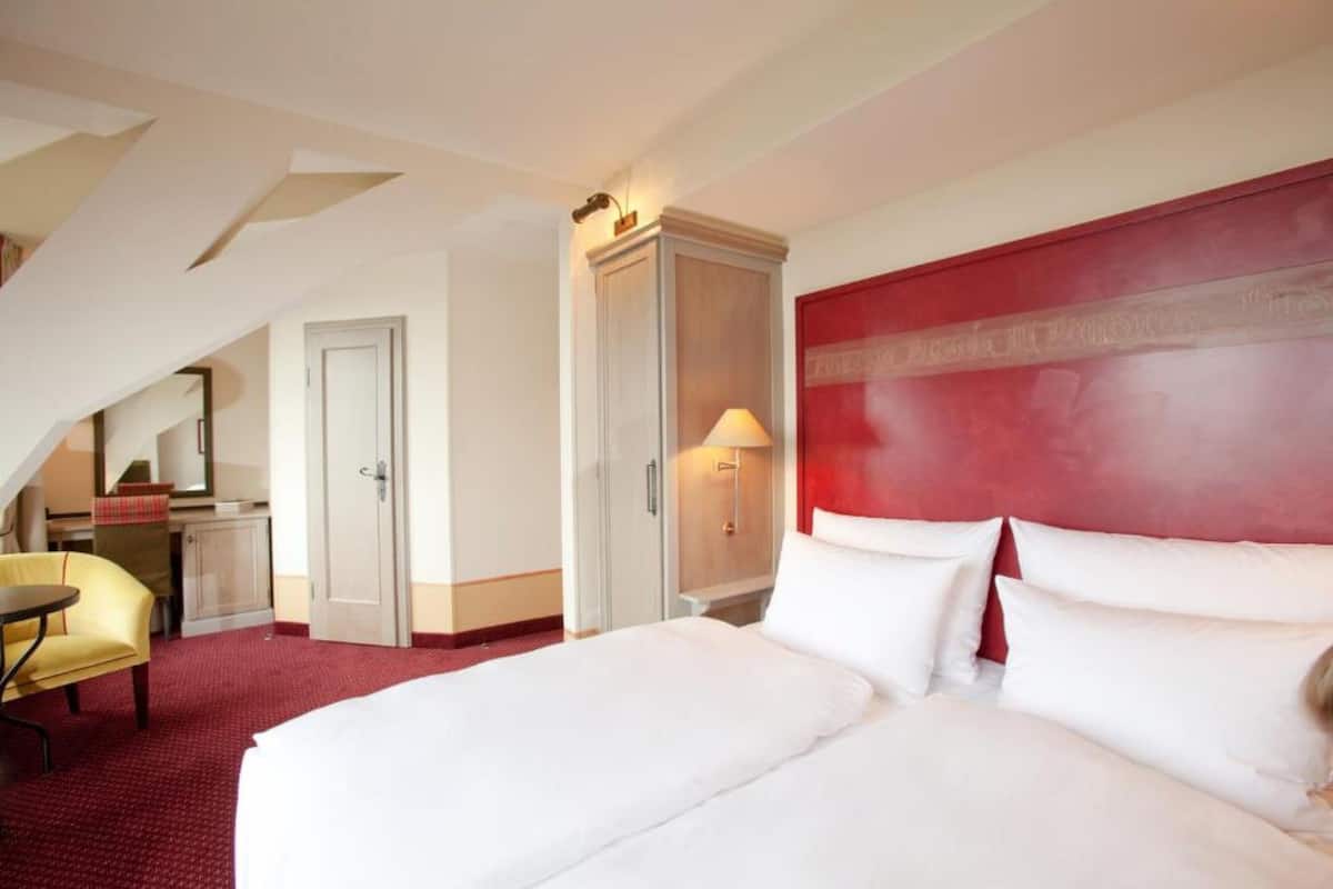 Ett hotellrum med en stor säng, ett skrivbord, en stol och en garderob.