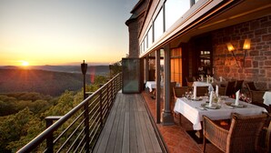 Ein Restaurant mit Außenbereich und Blick auf ein bewaldetes Tal, mit Backsteinwänden und großen Fenstern.