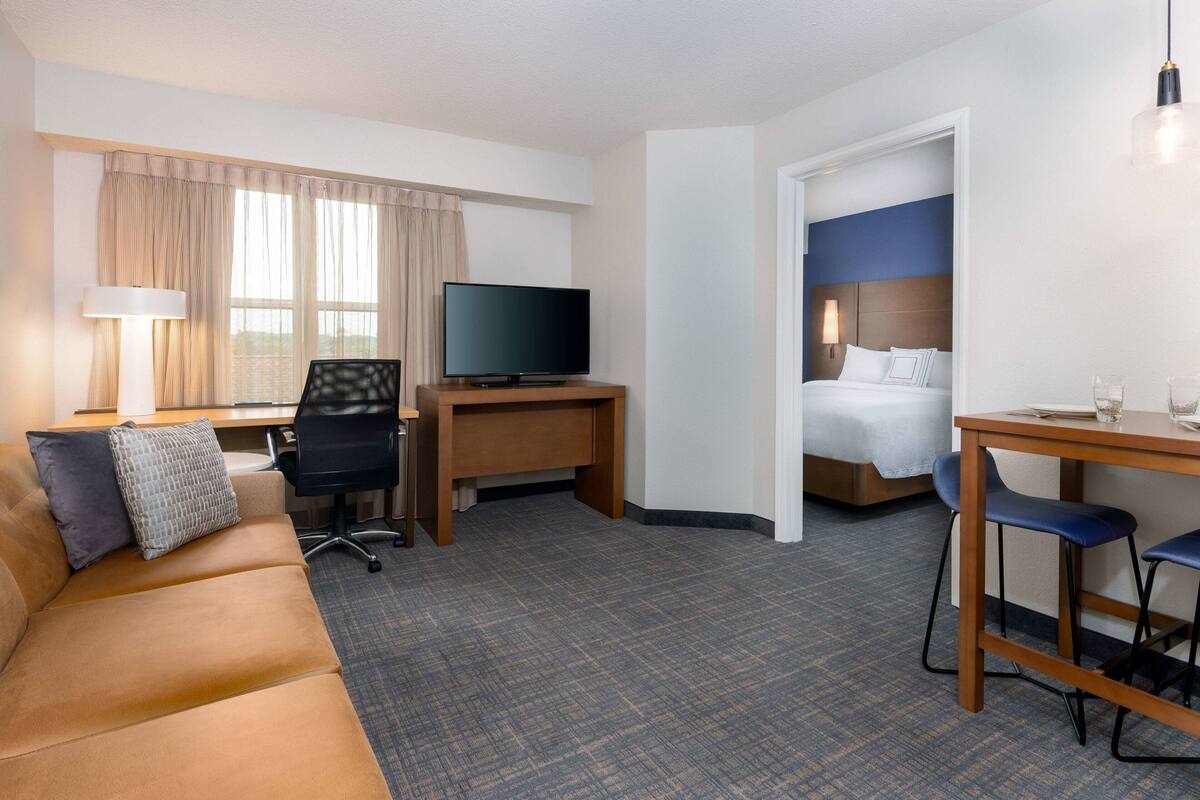 Een hotelkamer met een bank, een bureau met een televisie, een bed en een eethoek.