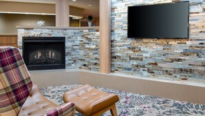 Una sala de estar moderna con chimenea, televisor montado en la pared y un sillón estampado.