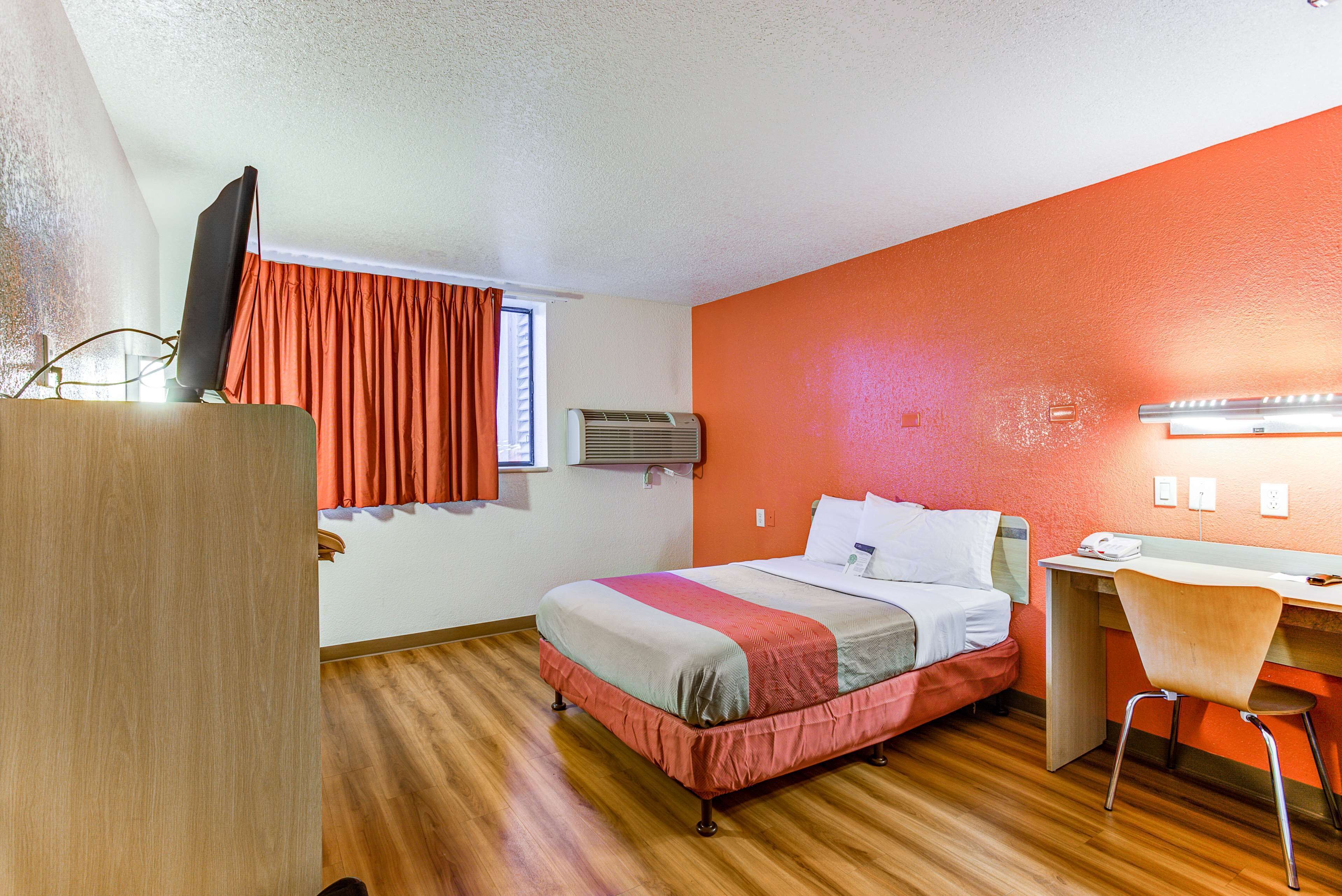 Una camera d'albergo con un letto, una scrivania, una sedia e un televisore su un mobile.