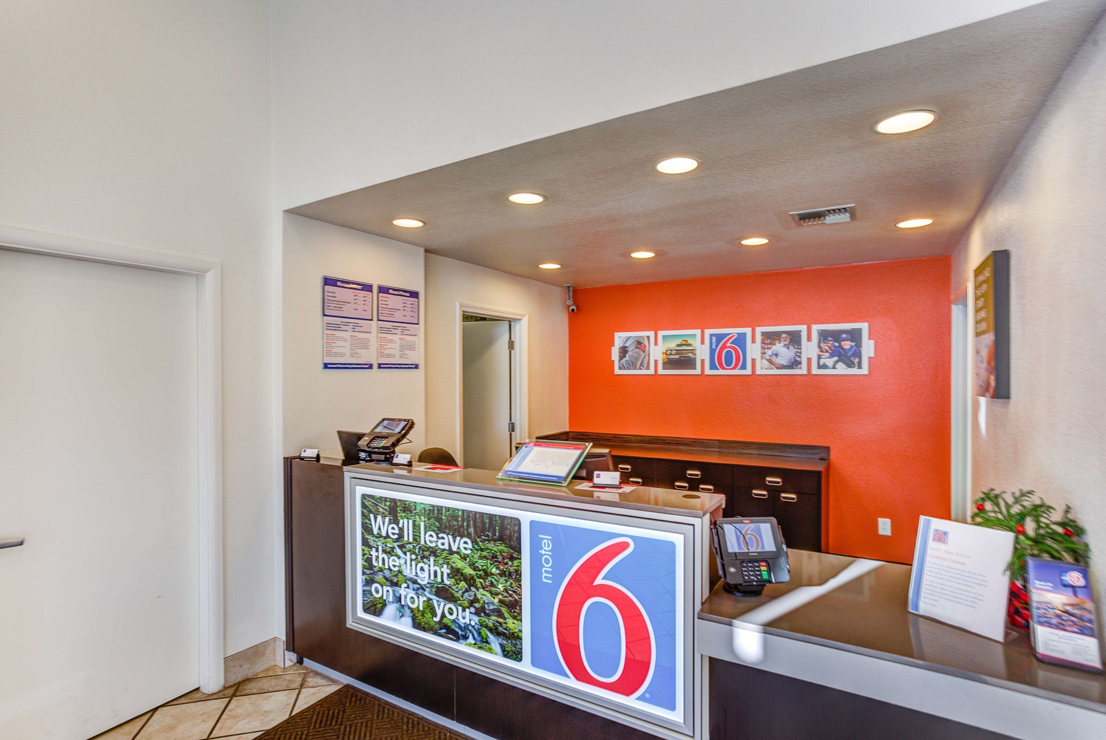 A hotel reception desk with a number 6 sign, a digital display, and a small plant.