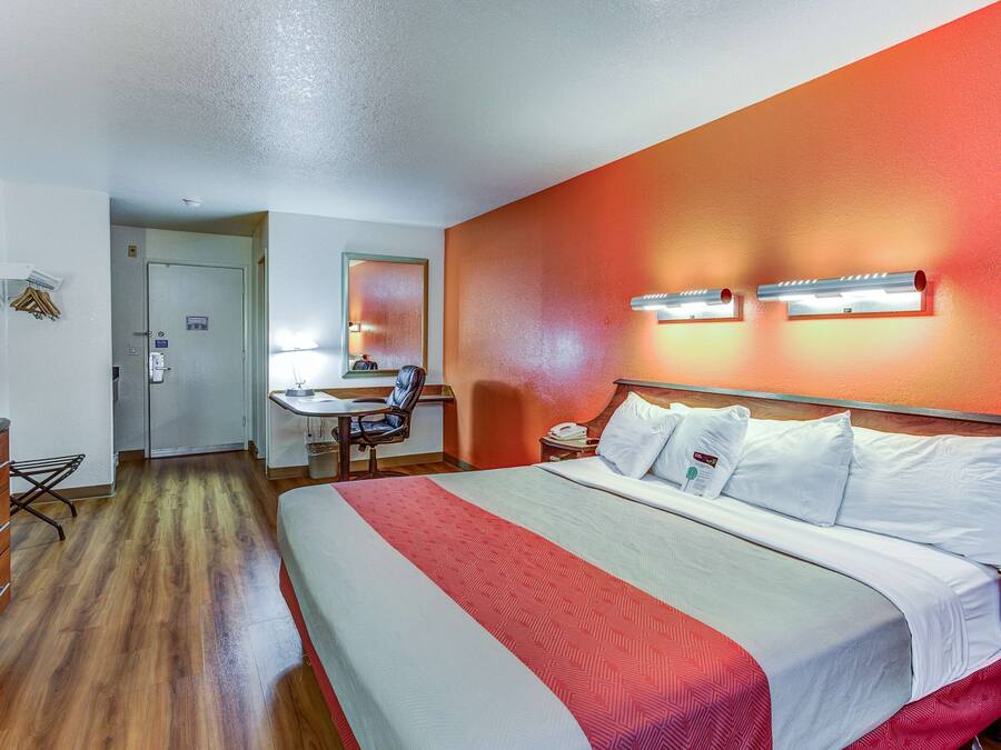 A hotel room with a large bed, a desk, and a chair.