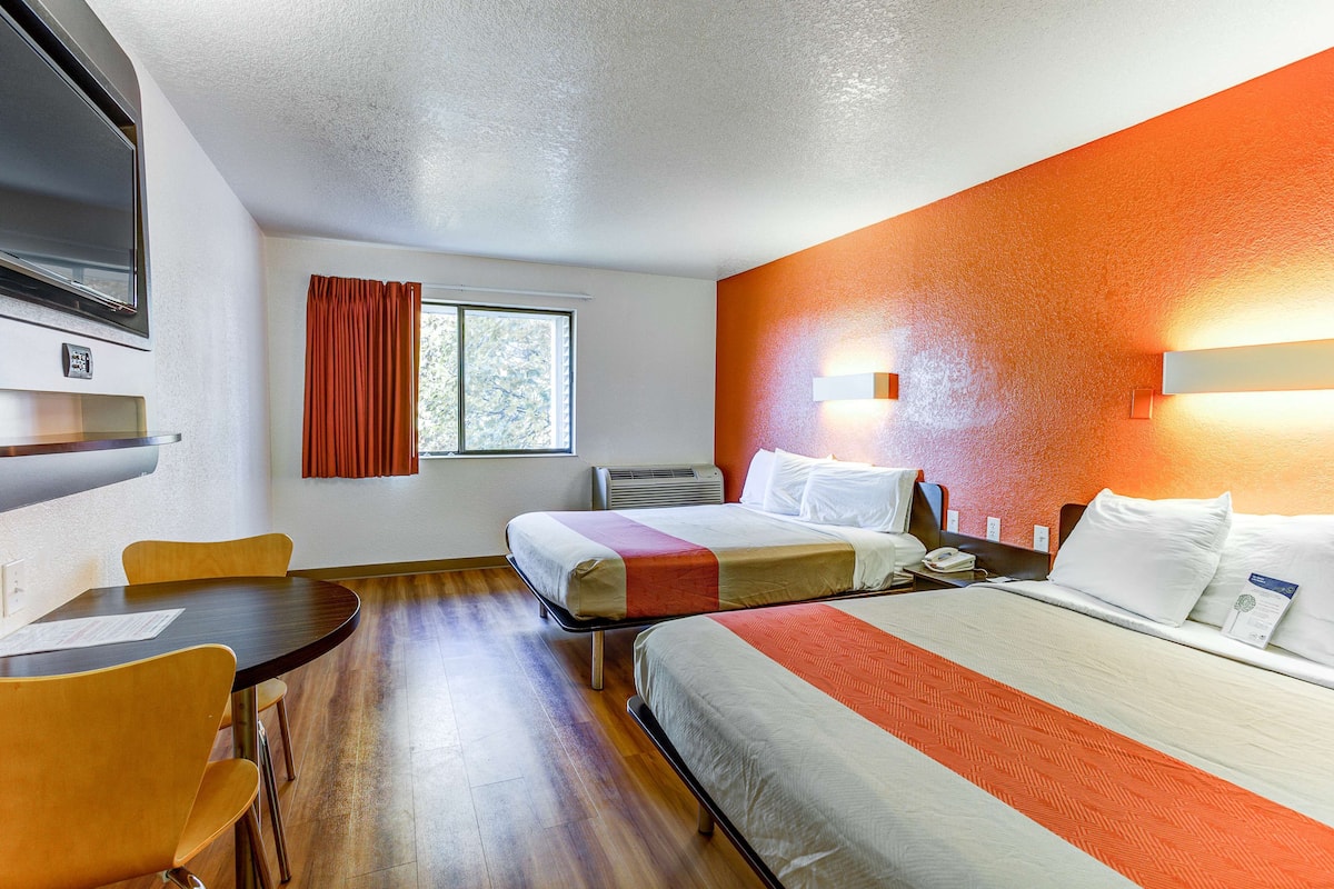A hotel room with two beds, a dining table, and chairs.