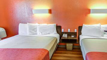 Ein Hotelzimmer mit zwei Betten, Holzboden, einem Nachttisch mit Telefon und einem Papierkorb.