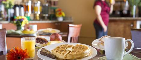 A breakfast setting with waffles, orange juice, and a cup on a table.