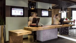 A reception desk with a wooden counter and a modern design. There are two screens above the desk displaying information.