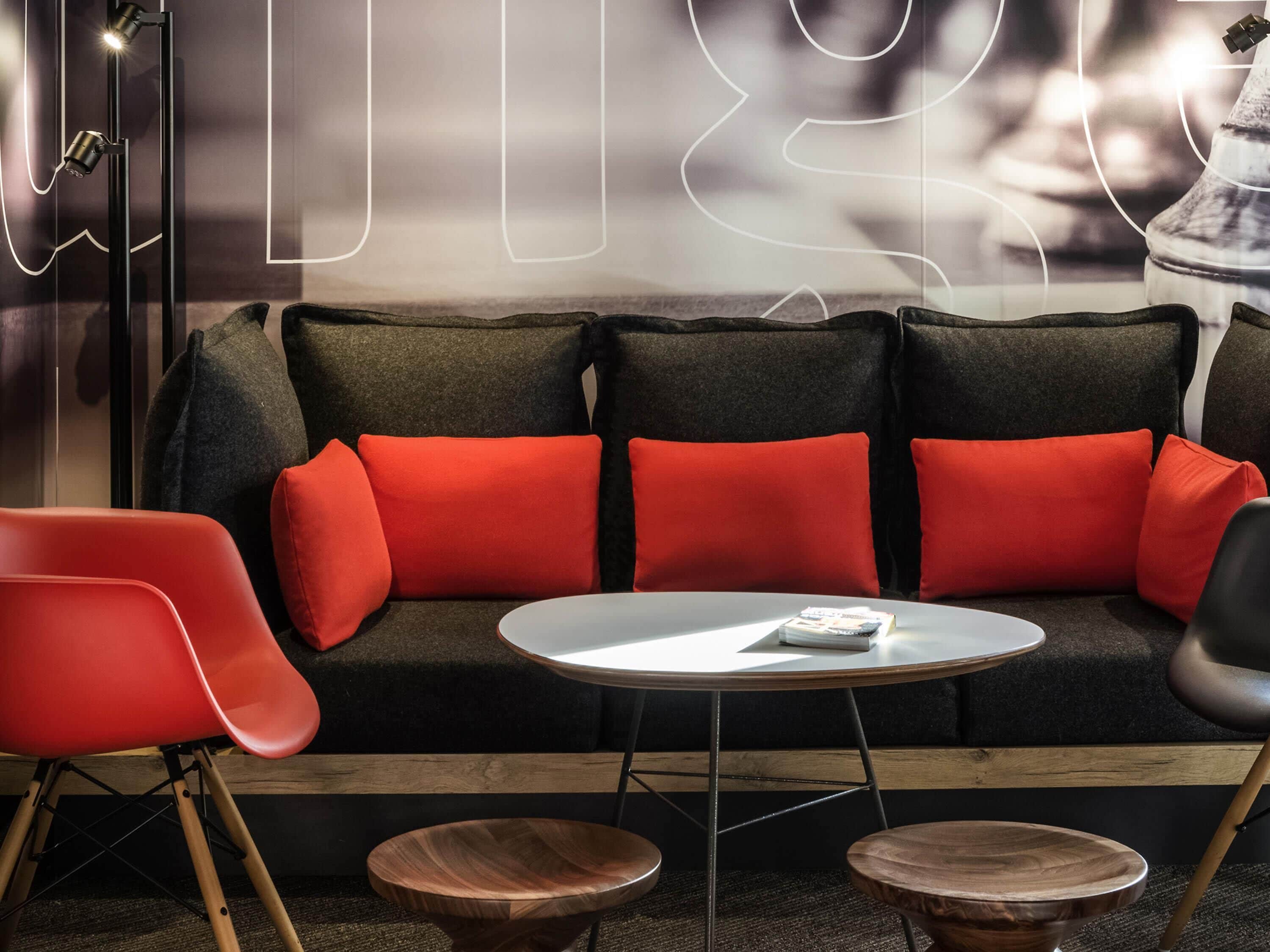 A modern living area with a dark sofa, red cushions, a white coffee table, and wooden side tables.