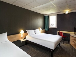 Una habitación de hotel con una cama grande, mesitas de noche con lámparas, un escritorio y una silla.