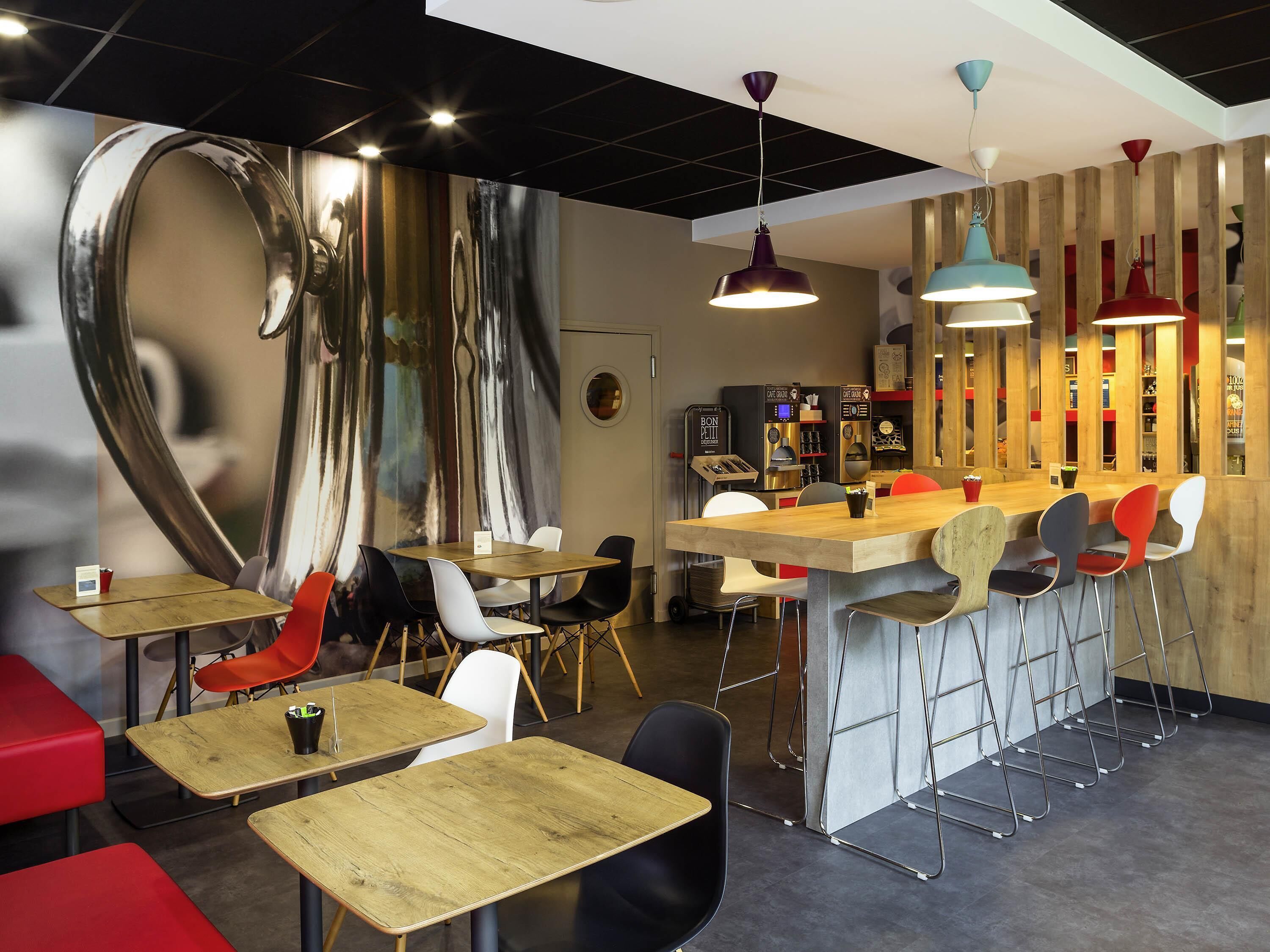 A modern cafe interior with a bar area, seating arrangements, and a large abstract wall art piece.