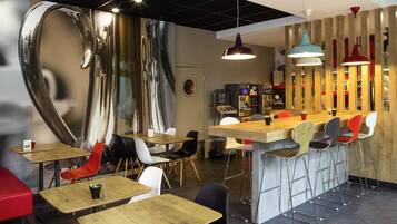 A modern cafe interior with a bar area, seating arrangements, and a large abstract wall art piece.