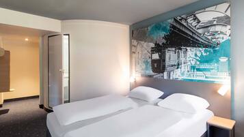 Une chambre d’hôtel avec un grand lit, une petite table de chevet et une fresque murale représentant un paysage urbain.