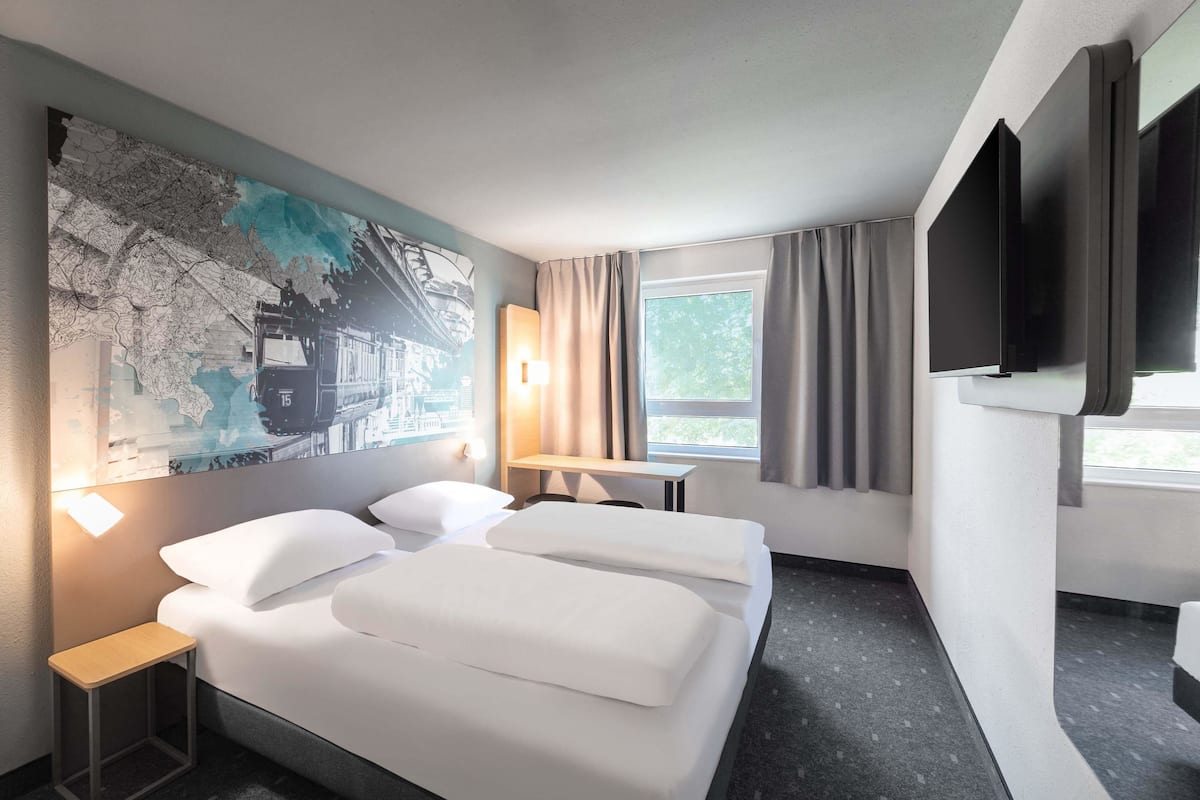 Ein Hotelzimmer mit einem großen Bett, einem Schreibtisch, einem Stuhl, einem Flachbildfernseher und Wandkunst mit einer Weltkarte.