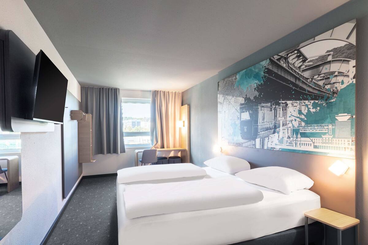 Ein modernes Hotelzimmer mit einem großen Bett, einem Schreibtisch und einem Fernseher.