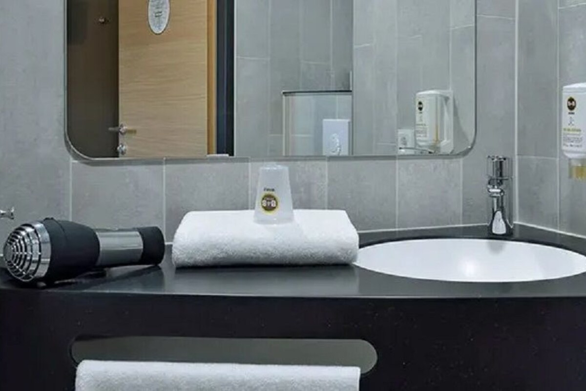 Une salle de bain moderne avec un lavabo rond, une serviette, un sèche-cheveux et un miroir.