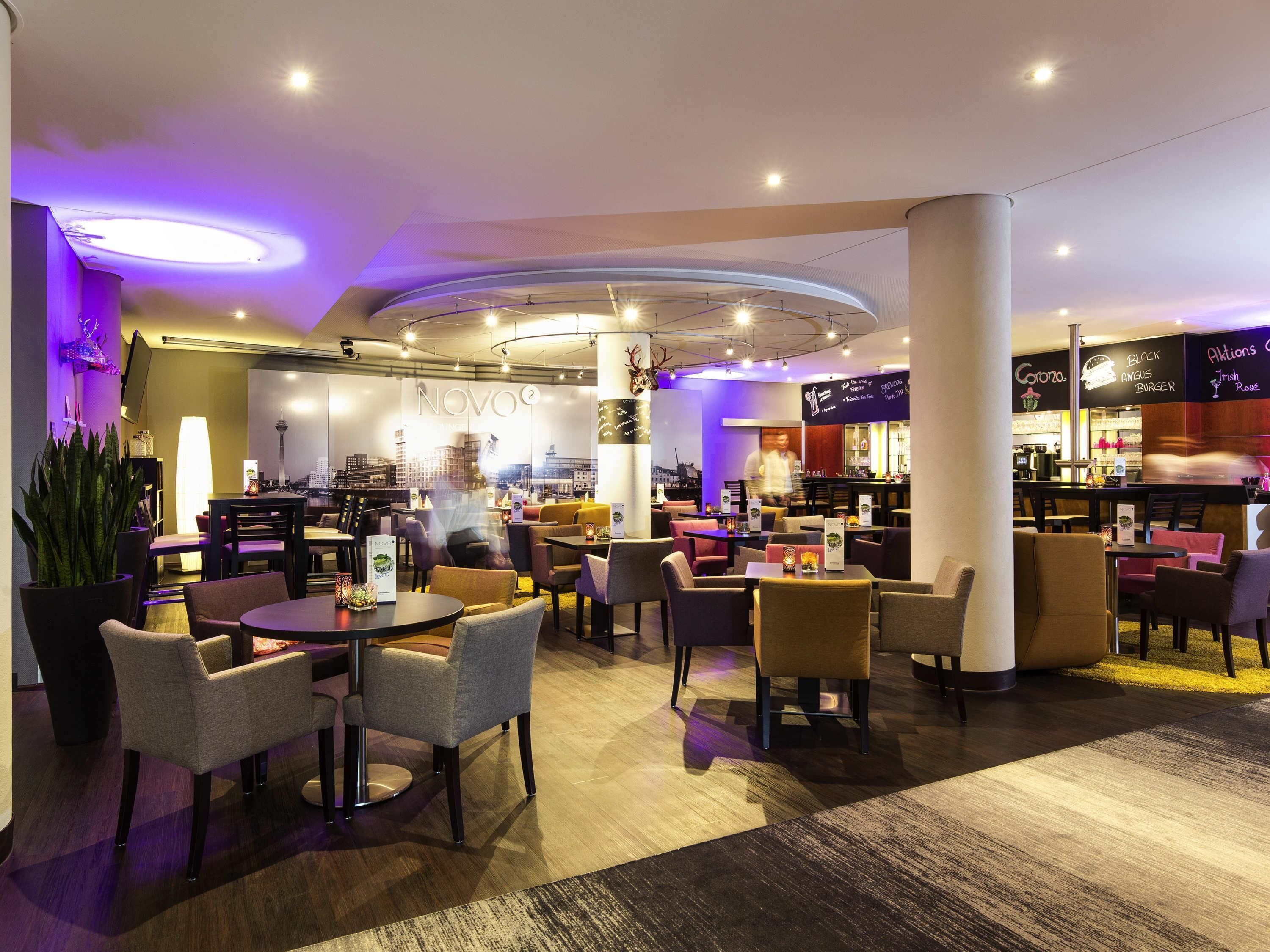 A modern restaurant with a city view, multiple seating areas, and a bar.