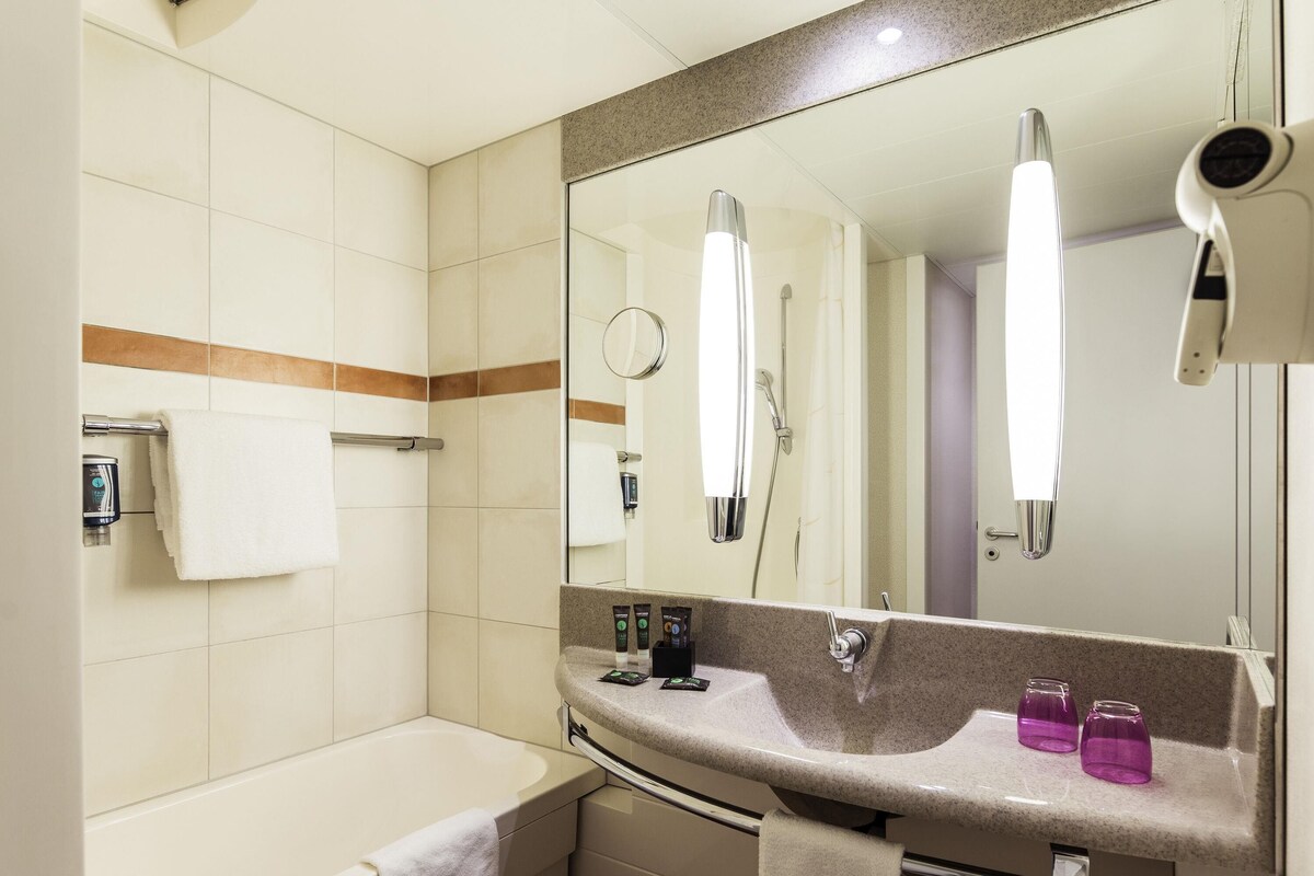 Une salle de bain moderne avec une baignoire, un meuble-lavabo avec un miroir et un porte-serviettes.
