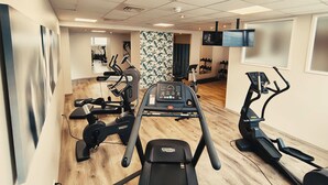 Un gimnasio con cintas de correr, elípticas y un espejo grande.