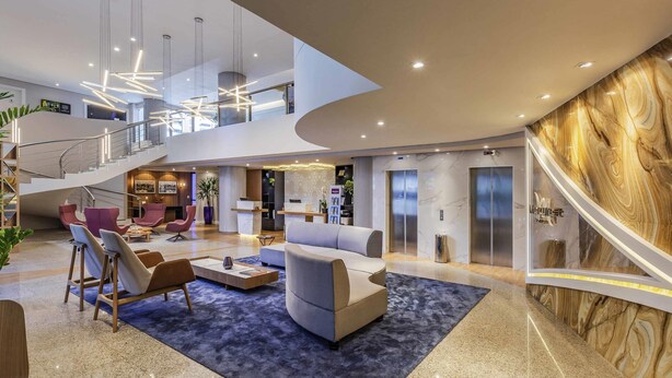 En rummelig lobby med et centralt siddeområde, en trappe og en reception.