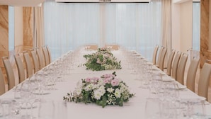 Una larga mesa de conferencias con sillas, centros de mesa florales y copas de vino vacías.