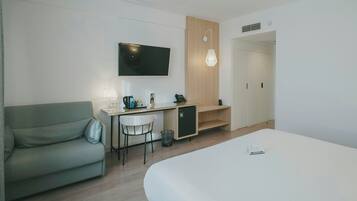 Una habitación de hotel moderna con una cama, un escritorio con una silla, un televisor y una pared de paneles de madera.