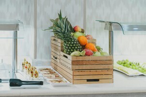 Una exhibición de frutas con cajas de madera, una mesa de vidrio y vistas al exterior.
