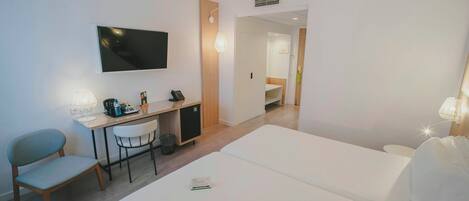 A hotel room with a bed, desk, chair, TV, and a bathroom visible through an open door.