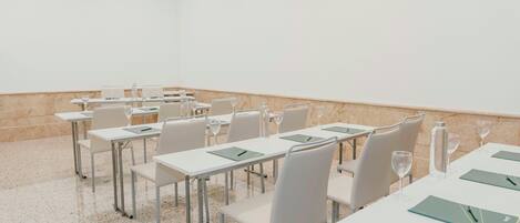 A conference room with white tables, chairs, and a marble floor.