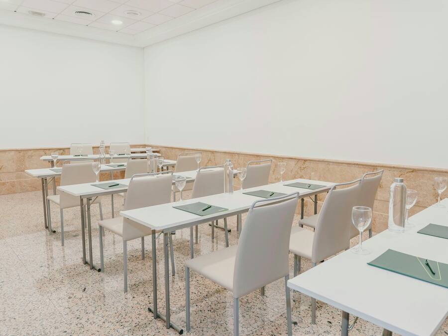 A conference room with white tables, chairs, and a marble floor.