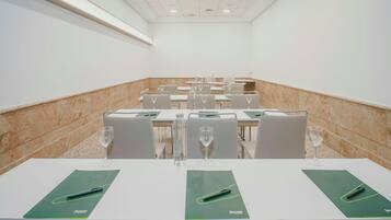 Un salón de conferencias con mesas, sillas y botellas de agua.
