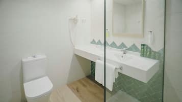 Un baño con inodoro, lavabo, cabina de ducha de cristal y espejo.